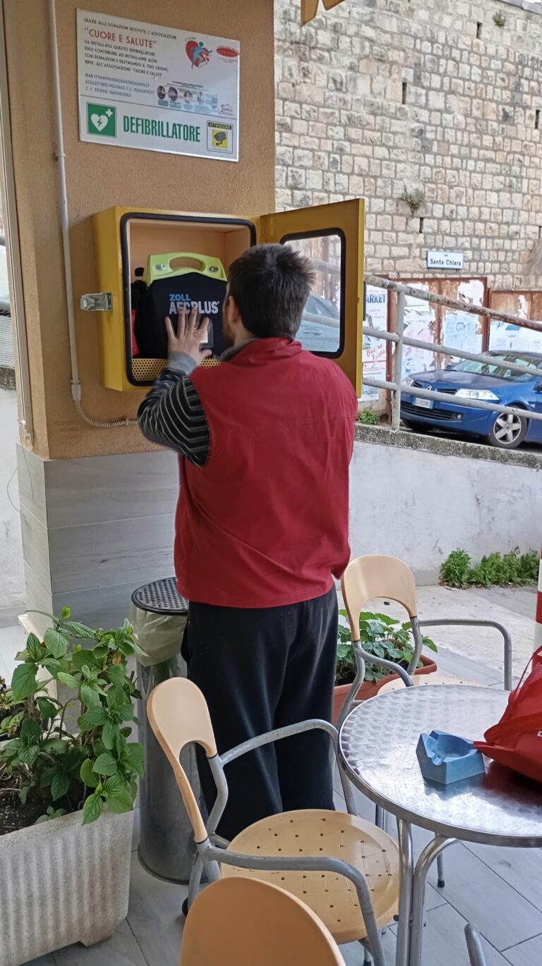 L'immagine mostra un operatore che controlla un defibrillatore installato nel pressi di un esercizio pubblico ad Avigliano